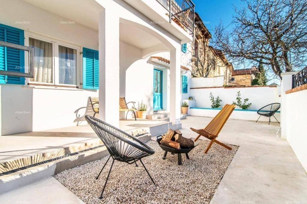 Gemütlicher Terrassenbereich mit Feuerstelle und modernen Stühlen vor der weißen Hausfassade.