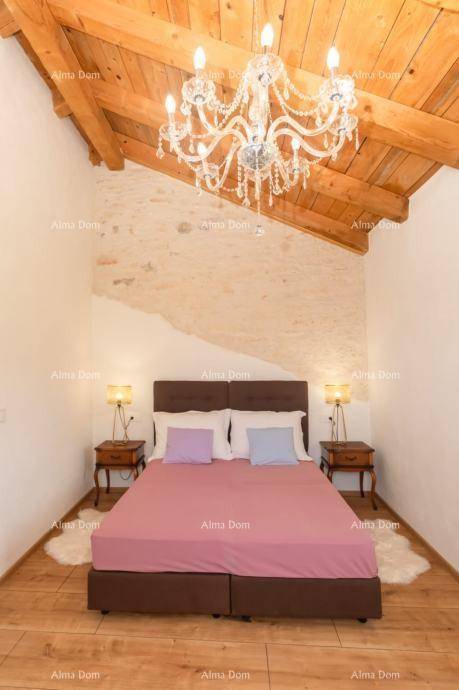Schlafzimmer mit Holzbalkendecke, rustikaler Steinwand und Parkettboden, gemütlich eingerichtet.