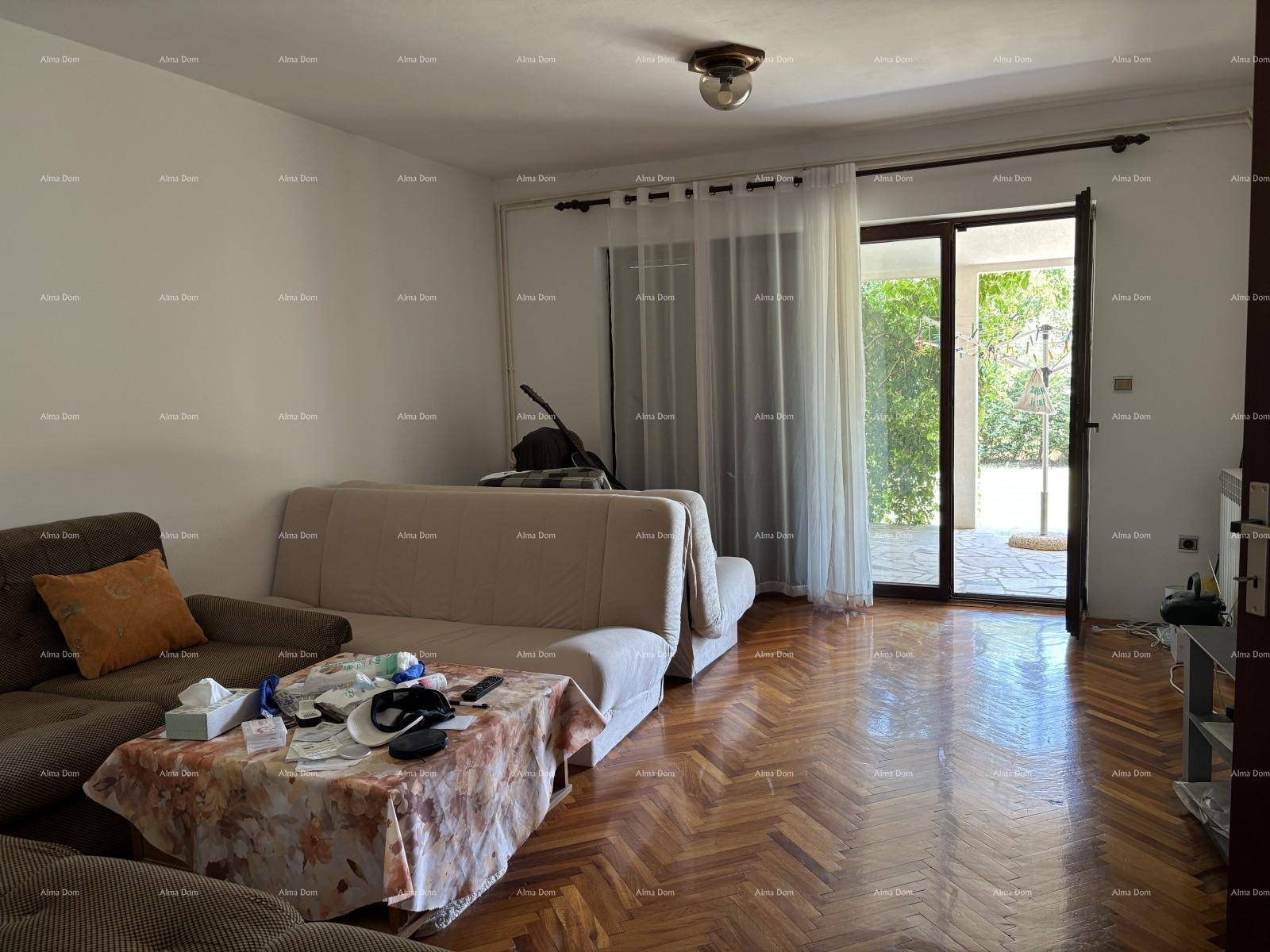 Gemütliches Wohnzimmer mit Parkettboden, Sofa und direktem Zugang zur überdachten Terrasse.