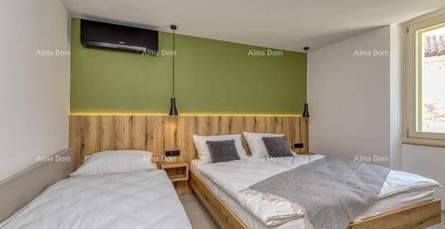 Helles Schlafzimmer mit Doppelbett, Einzelbett, grüner Akzentwand und Klimaanlage.