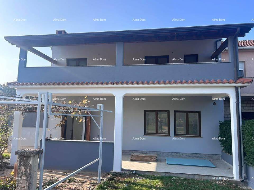 Modernes Wohnhaus mit überdachter Terrasse im Erdgeschoss und Balkonen im Obergeschoss.