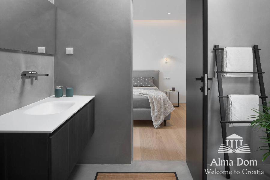 Modernes Badezimmer mit Waschtisch und direktem Zugang zum Schlafzimmer, ausgestattet mit Handtuchleiter.