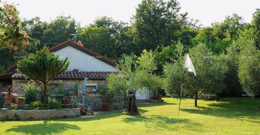 Traditionelles Steinhaus umgeben von einem weitläufigen Rasen und zahlreichen Bäumen.