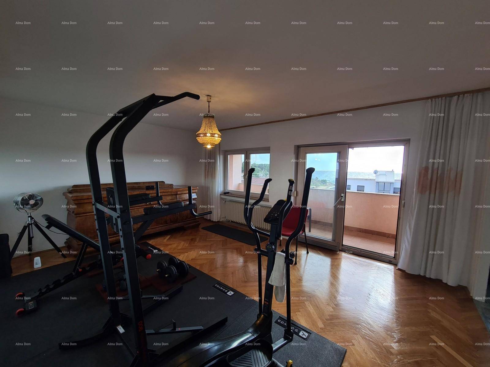 Geräumiger Raum, der als Fitnessbereich genutzt wird, mit Parkettboden und Balkonzugang.