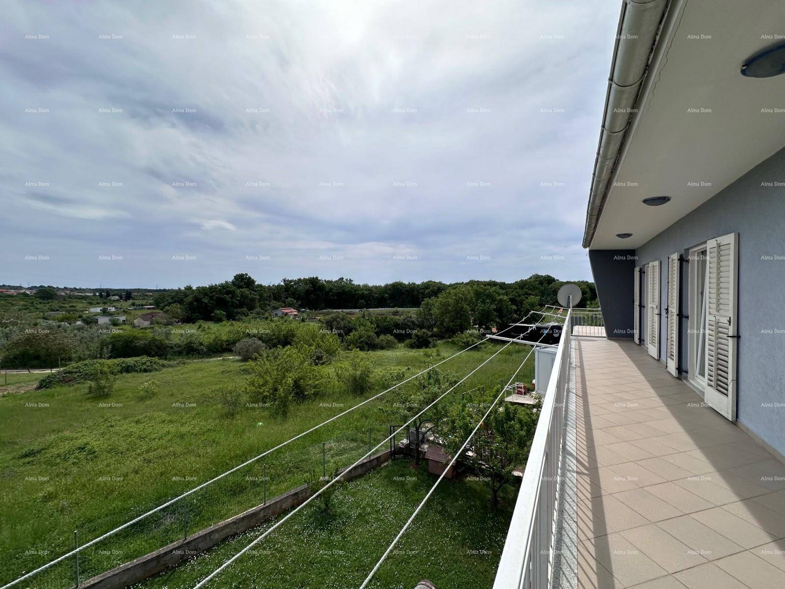 Langer Balkon mit weitem Blick über grüne Landschaft und entfernte Häuser.