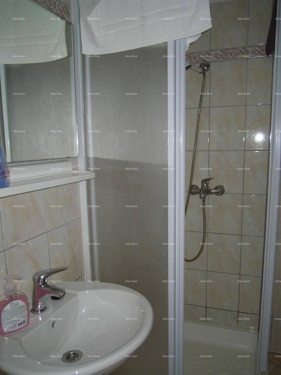 Kleines Badezimmer mit Duschkabine, Waschbecken und hellen Fliesen an den Wänden und auf dem Boden.