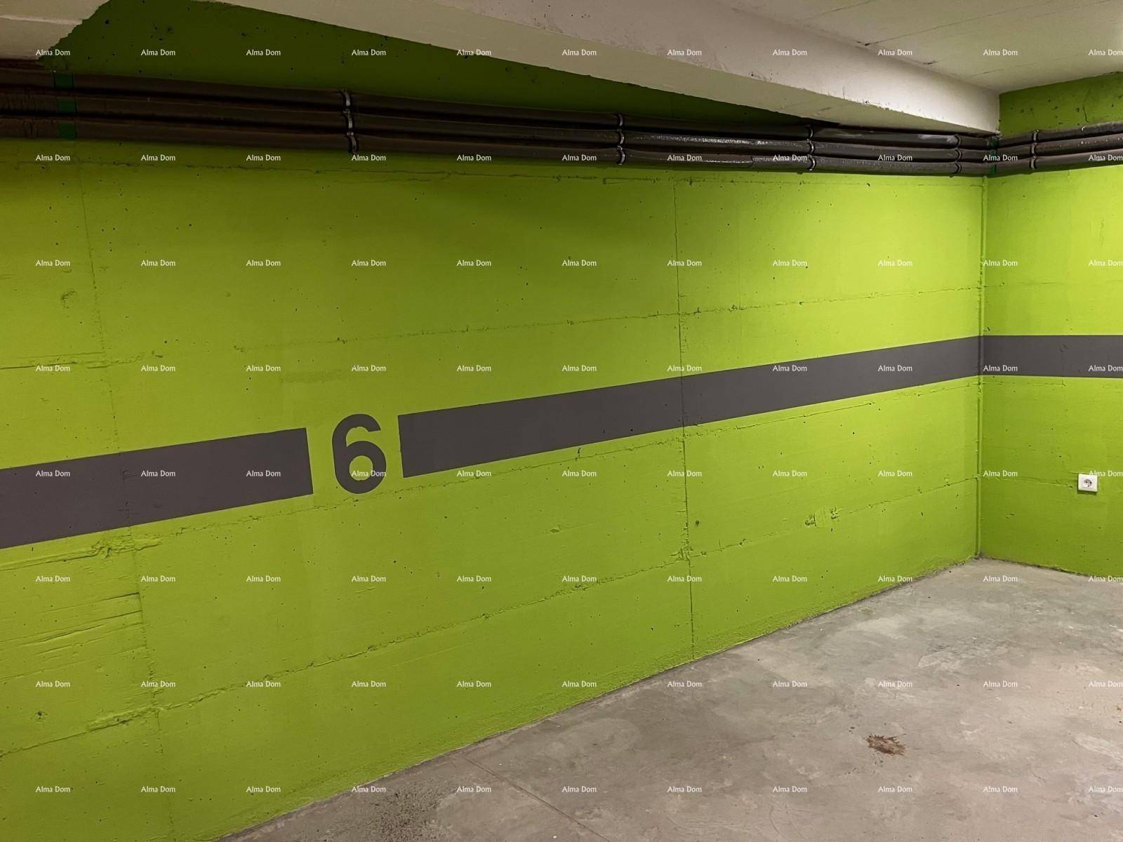 Heller Bereich in der Tiefgarage mit grünen Wänden und markiertem Stellplatz Nummer sechs.