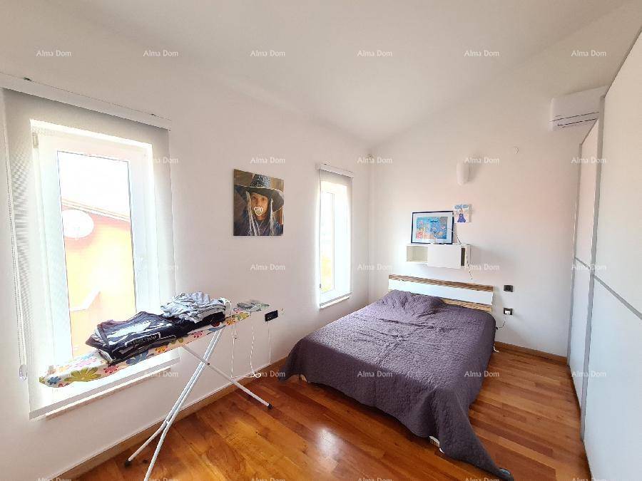 Helles Schlafzimmer mit Holzboden, großen Fenstern und einem modernen Bett.