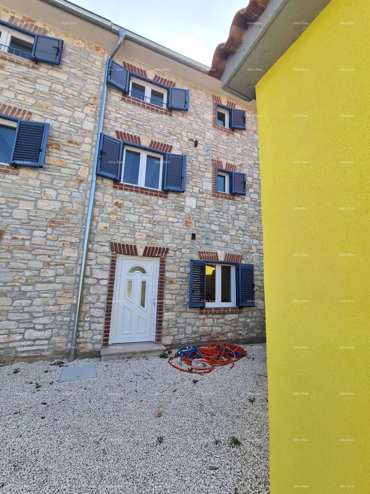 Ansicht der Steinfassade mit blauen Fensterläden und einem Teil der gelben Seitenwand.