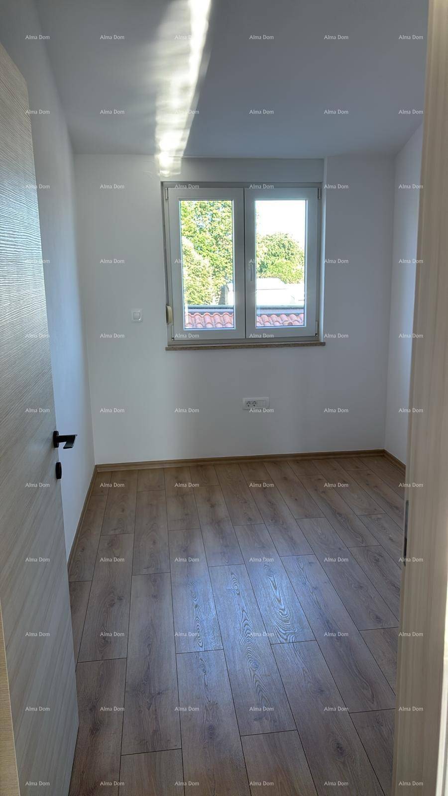 Helles Schlafzimmer mit modernem Laminatboden und einem Fenster mit Blick ins Grüne.