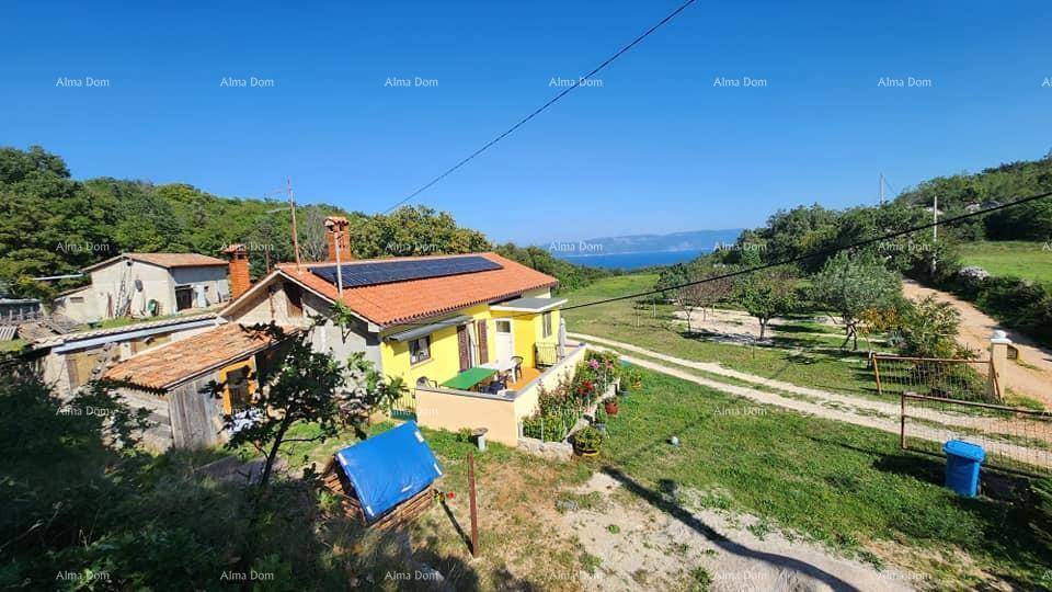 Gelbes Haus mit Solarpaneelen und weitem Blick auf die Landschaft und das Meer im Hintergrund.