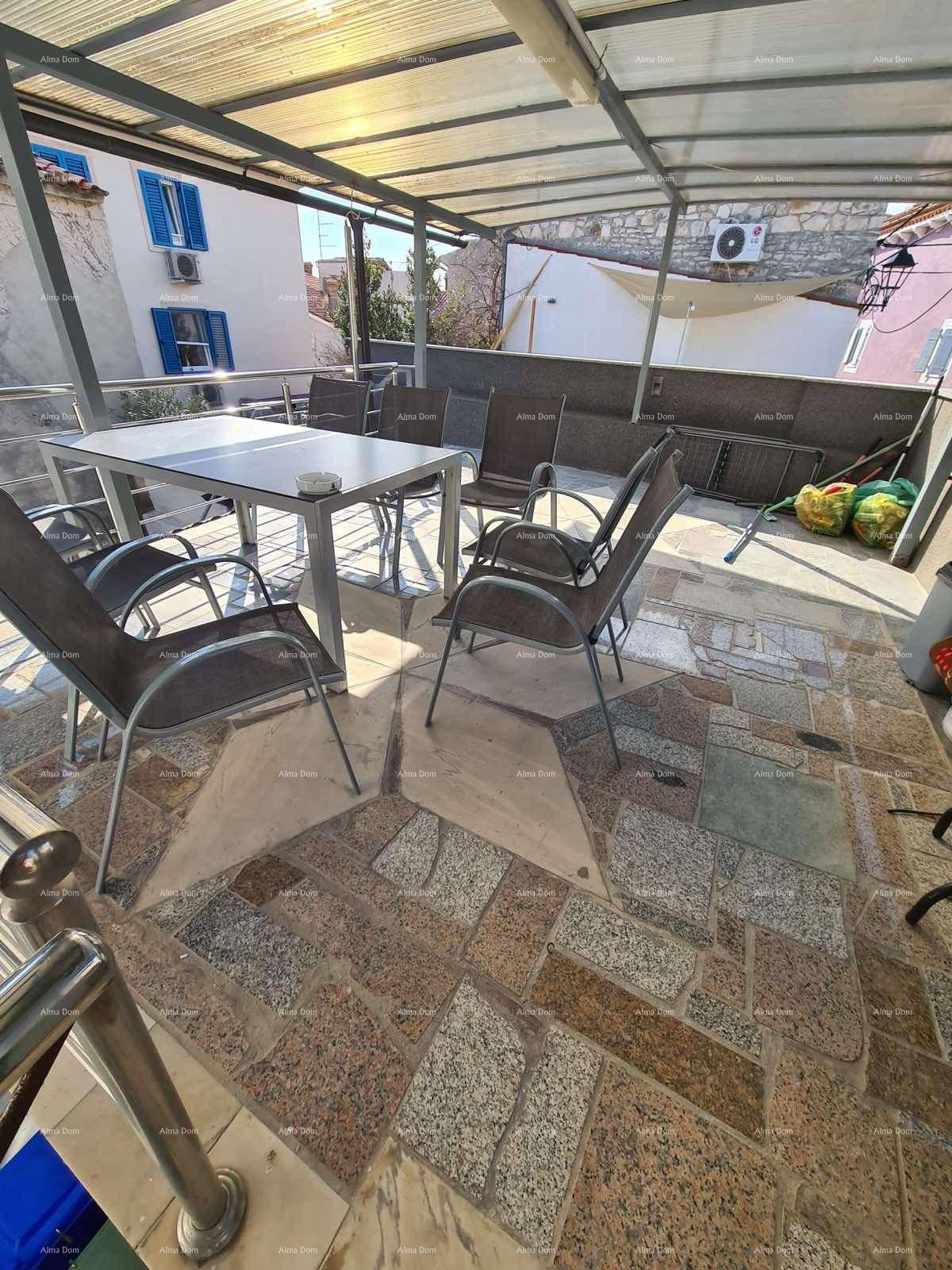 Sonniger Terrassenbereich mit Esstisch und Stühlen, gefliest mit Natursteinplatten.