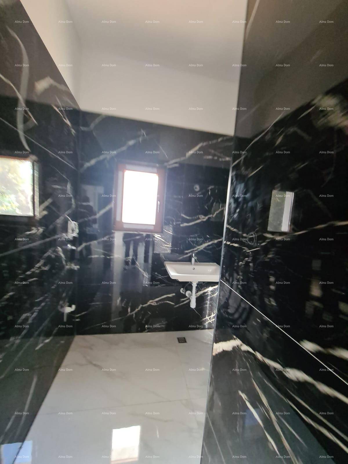 Modernes Badezimmer mit schwarzen Marmorfliesen, Waschbecken und einem Fenster für Tageslicht.