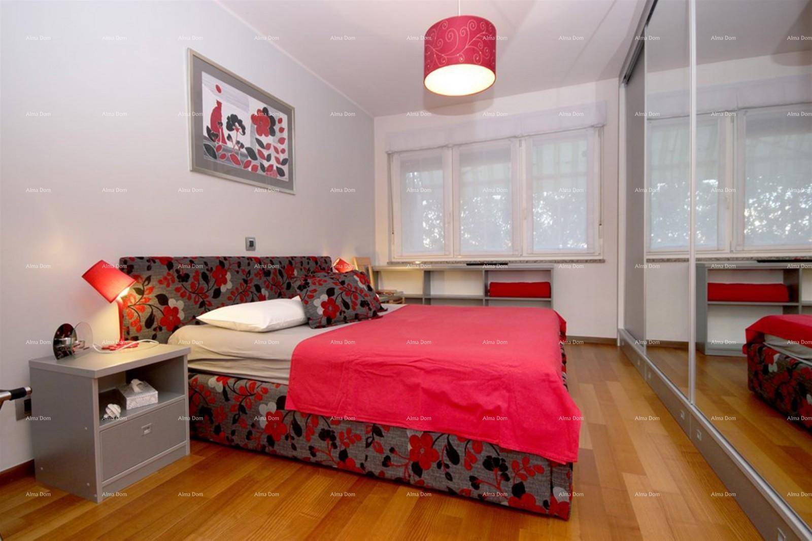 Helles Schlafzimmer mit rotem Bett, Nachttisch und großem Spiegelschrank.
