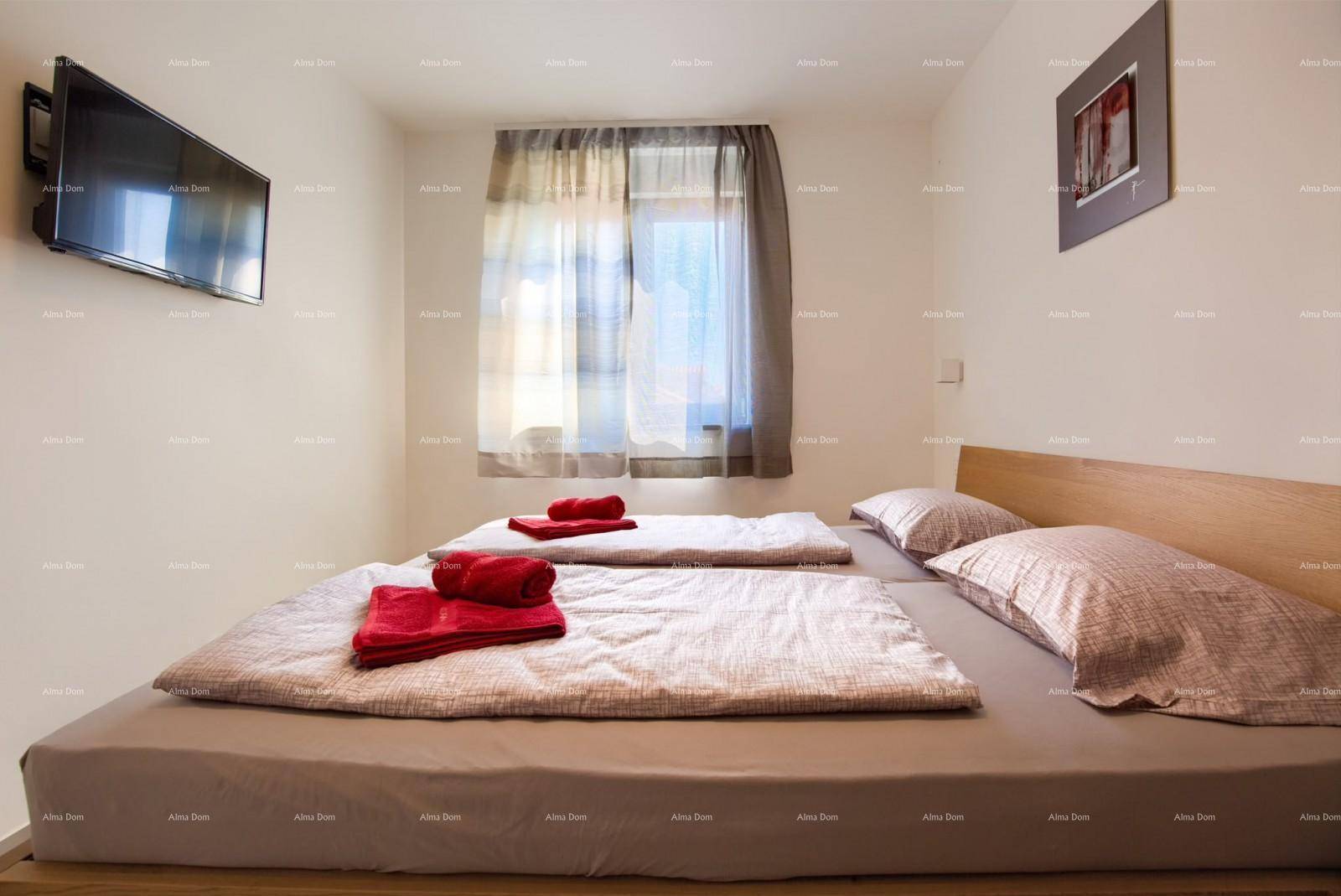 Gemütliches Schlafzimmer mit Doppelbett, Wandfernseher und Fenster mit Vorhängen für angenehmes Licht.