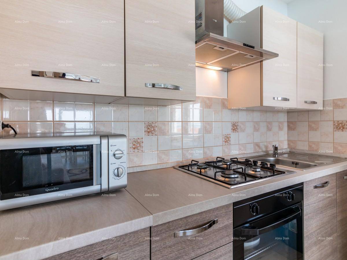 Detailansicht der modernen Küche mit Gasherd, Backofen, Mikrowelle und hellen Fliesen.