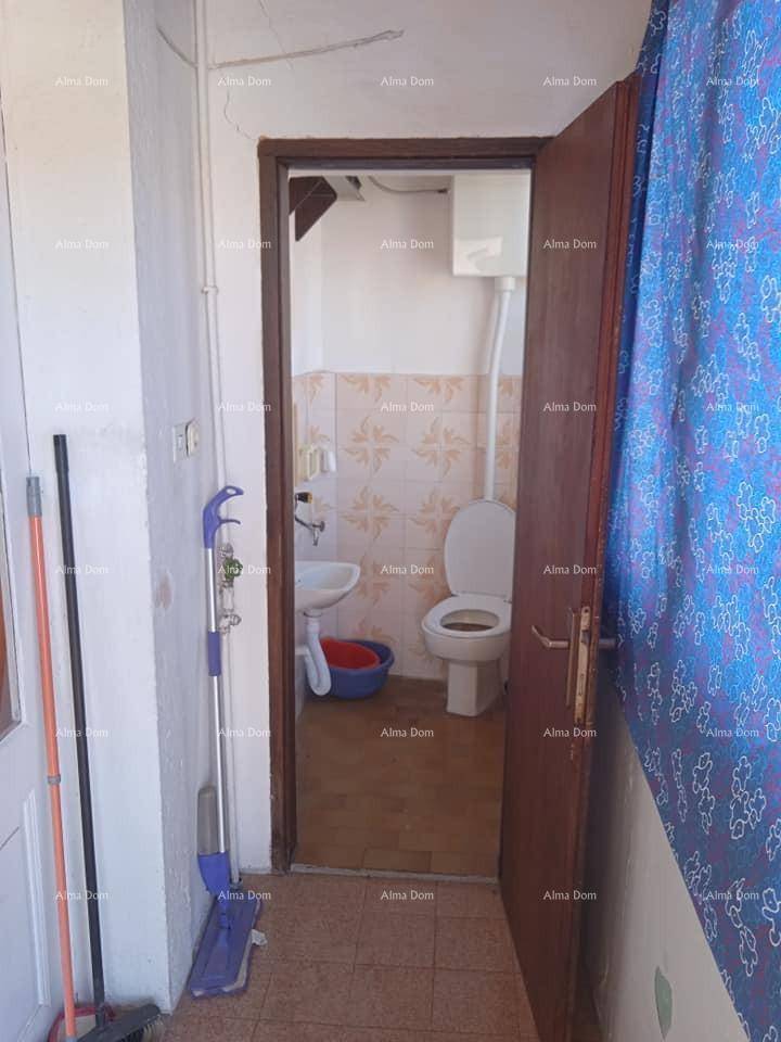 Kleines WC mit Toilette, Waschbecken und hell gemusterten Fliesen, zugänglich durch eine Holztür.