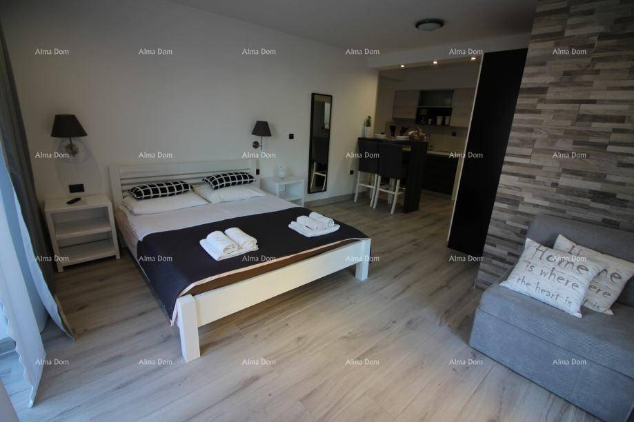 Modernes Schlafzimmer mit Doppelbett, Holzboden und integrierter Küchenzeile.