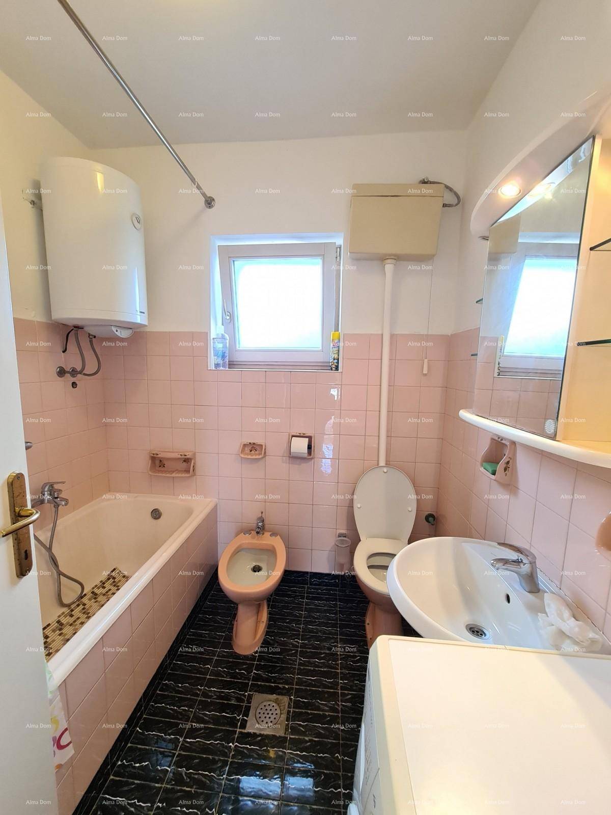 Badezimmer mit Badewanne, Bidet und Waschbecken, ausgestattet mit rosa Fliesen.