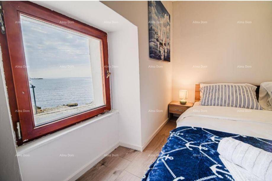 Schlafzimmer mit Holzboden, gemütlichem Bett und direktem Blick auf das Meer.