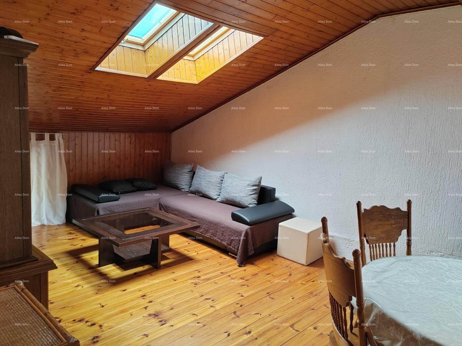 Gemütlicher Wohnbereich im Dachgeschoss mit Sofa, Couchtisch, Holzboden und Dachfenstern.