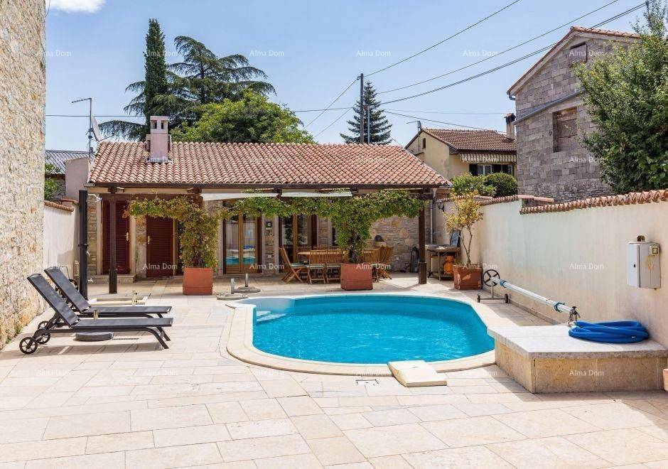 Sonniger Außenbereich mit Pool, Liegestühlen und einem charmanten Gebäude mit überdachter Terrasse.
