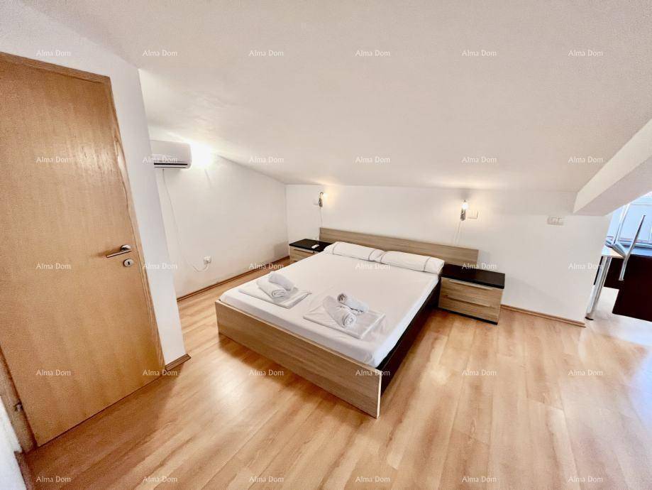 Dachgeschoss-Schlafzimmer mit Doppelbett, Holzboden und Klimaanlage für angenehmes Klima.