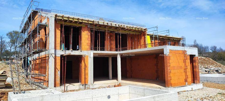Rohbau eines Hauses mit Gerüst und vorbereitetem Poolbereich unter blauem Himmel.
