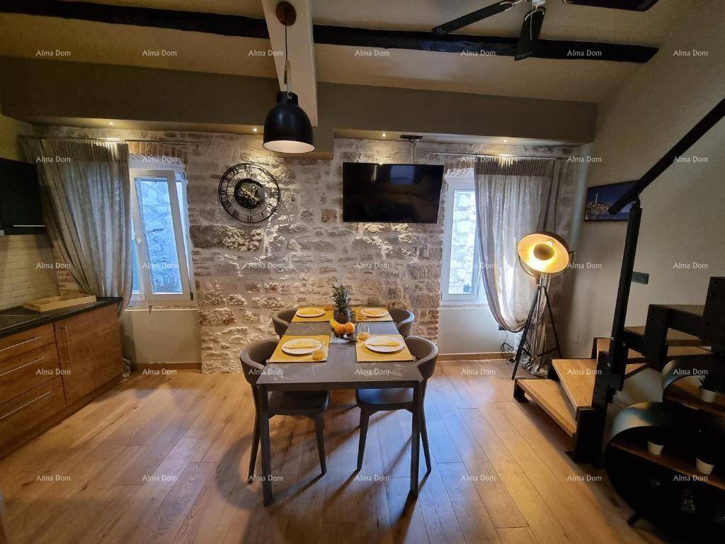 Essbereich mit gedecktem Tisch für vier Personen, rustikaler Steinwand und offener Treppe, die zum oberen Bereich führt.