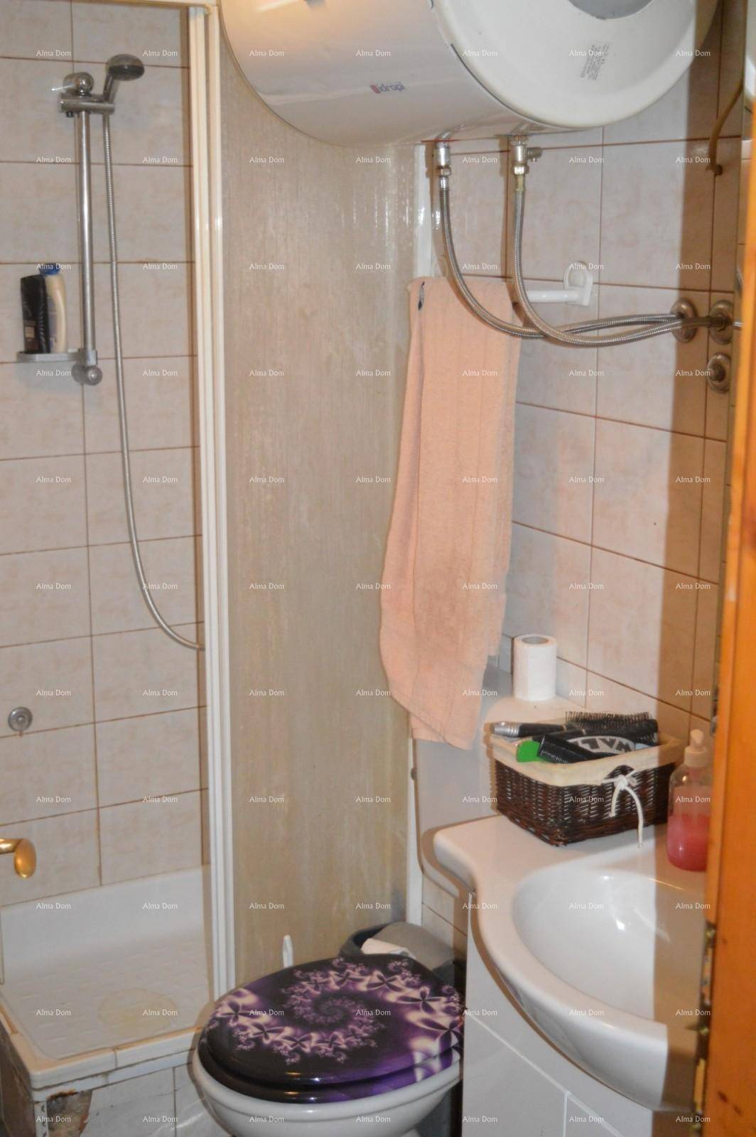 Kleines Badezimmer mit Duschkabine, Toilette und Waschbecken, komplett gefliest.
