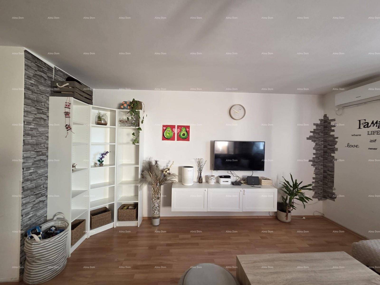 Geräumiges Wohnzimmer mit Holzboden, weißen Regalen und dekorativer Steinwand.