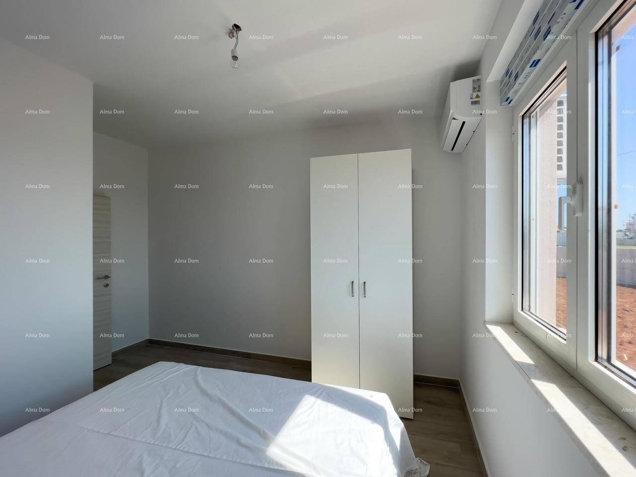 Schlafzimmer mit weißem Kleiderschrank, Klimaanlage und einem großen Fenster, das den Raum erhellt.