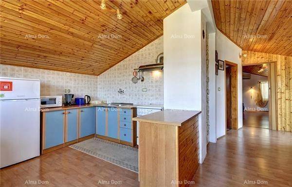 Küche mit blauen Schränken, Holzbalkendecke und Kühlschrank, offen zum Essbereich.