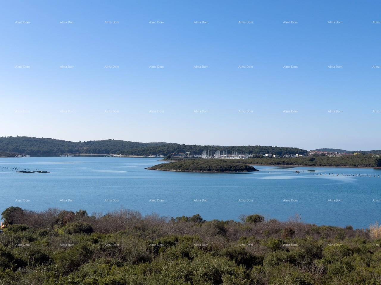 Panoramablick auf die ruhige Bucht mit kleinen Inseln und einem Yachthafen in der Ferne.