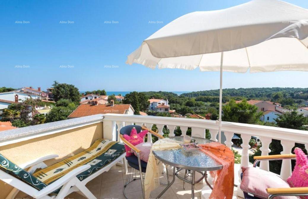 Möblierter Balkon mit Sonnenschirm, Liegestuhl und weitem Blick auf das Meer.
