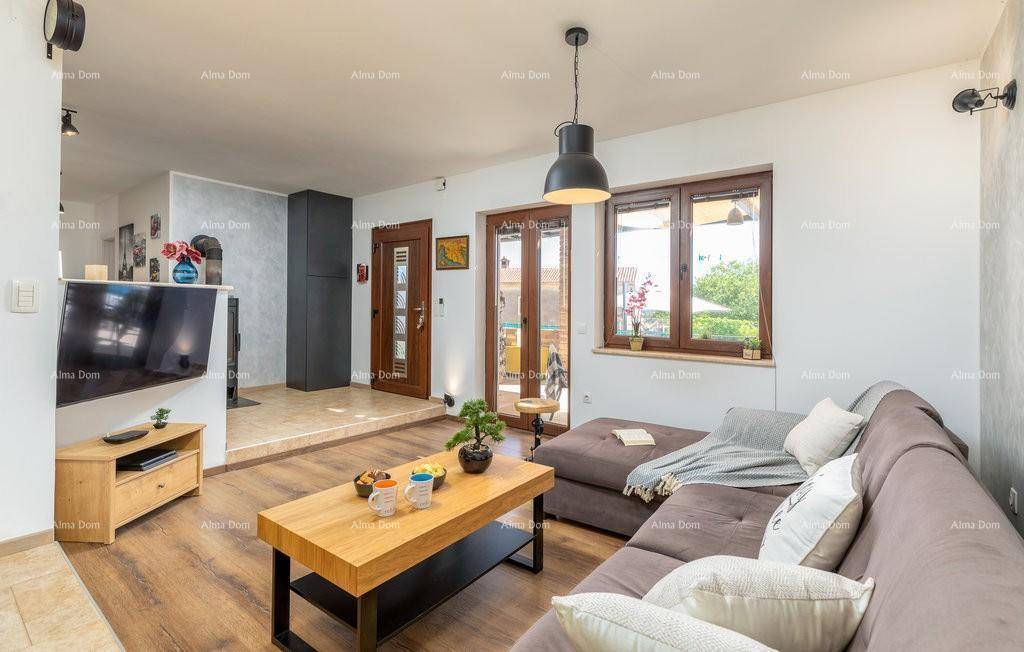 Heller Wohnbereich mit großem Ecksofa, Holzboden und Zugang zu einem Balkon durch Glastüren.