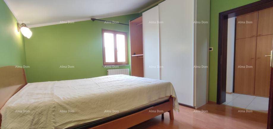 Schlafzimmer mit grün gestrichenen Wänden, Bett und weißem Kleiderschrank.