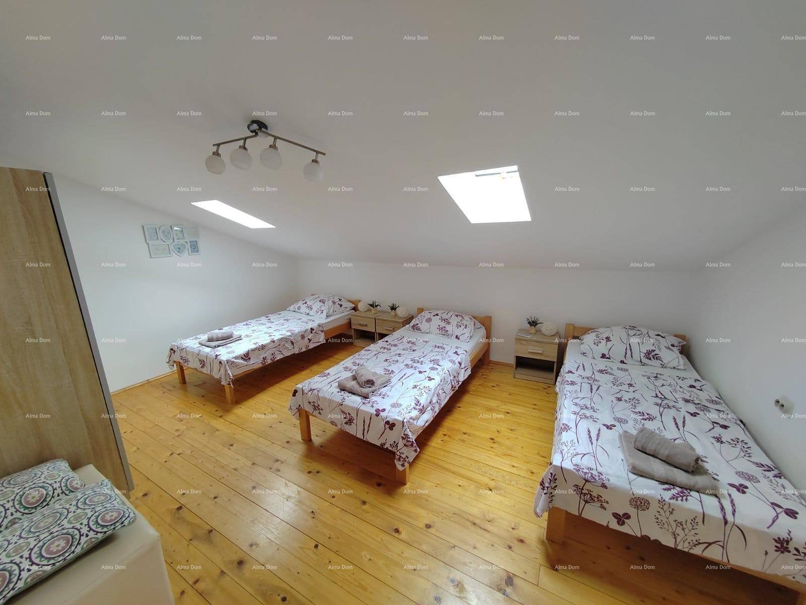 Helles Schlafzimmer im Dachgeschoss mit drei Einzelbetten, Holzboden und Dachfenstern.