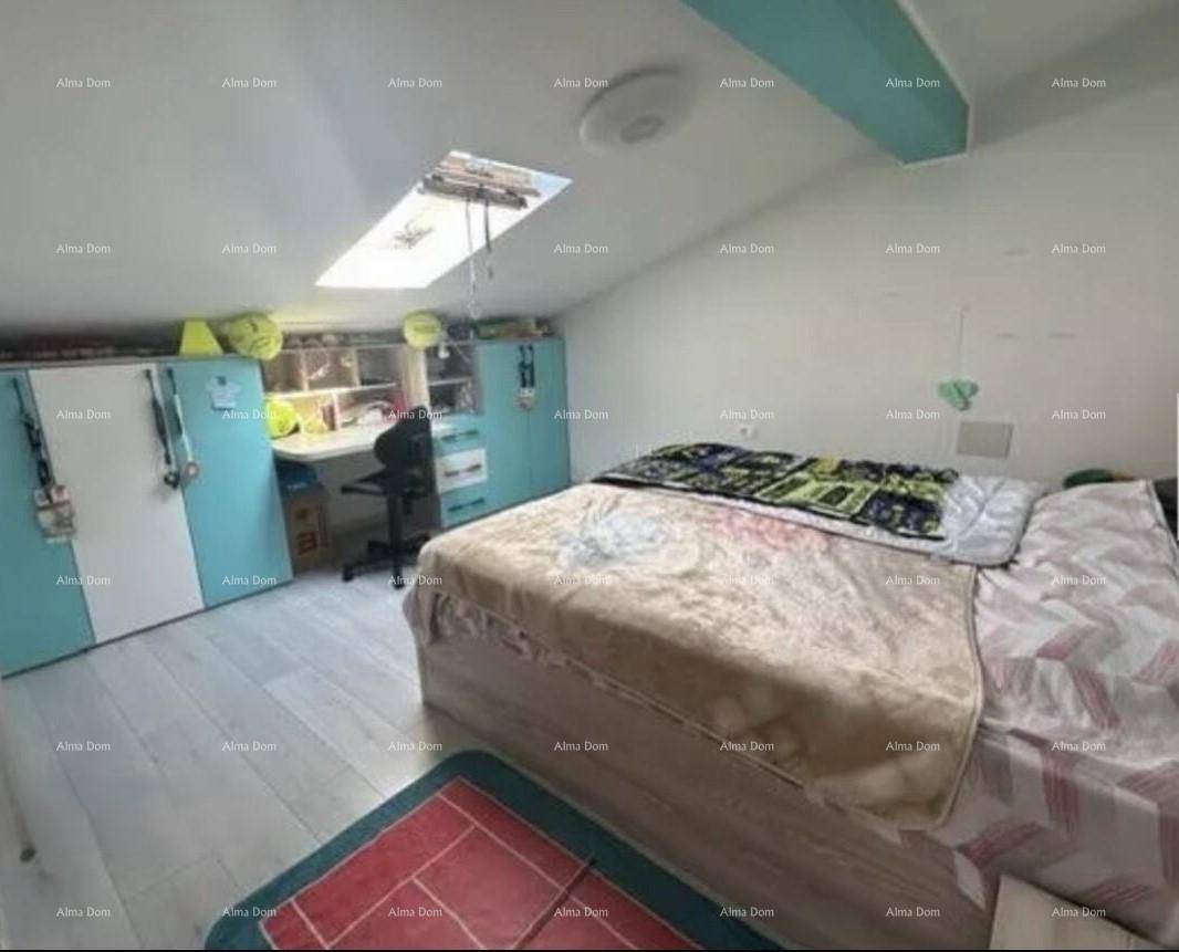 Helles Schlafzimmer mit Bett, Schreibtisch, Kleiderschrank und Dachfenster unter einer Schräge.