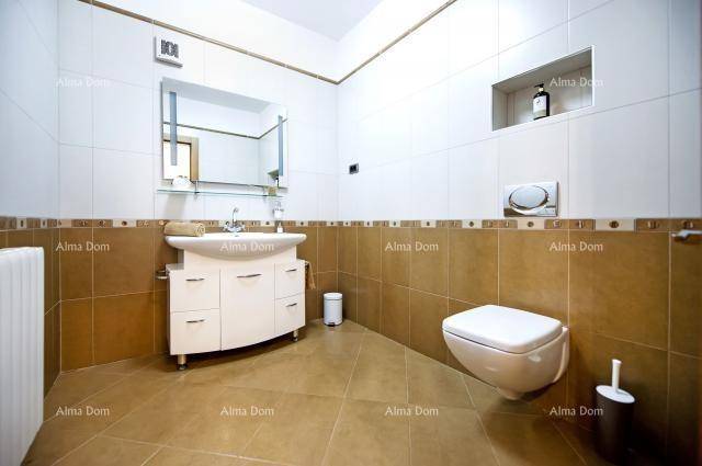 Badezimmer mit beigen Fliesen, wandhängendem WC und Einzelwaschbecken.