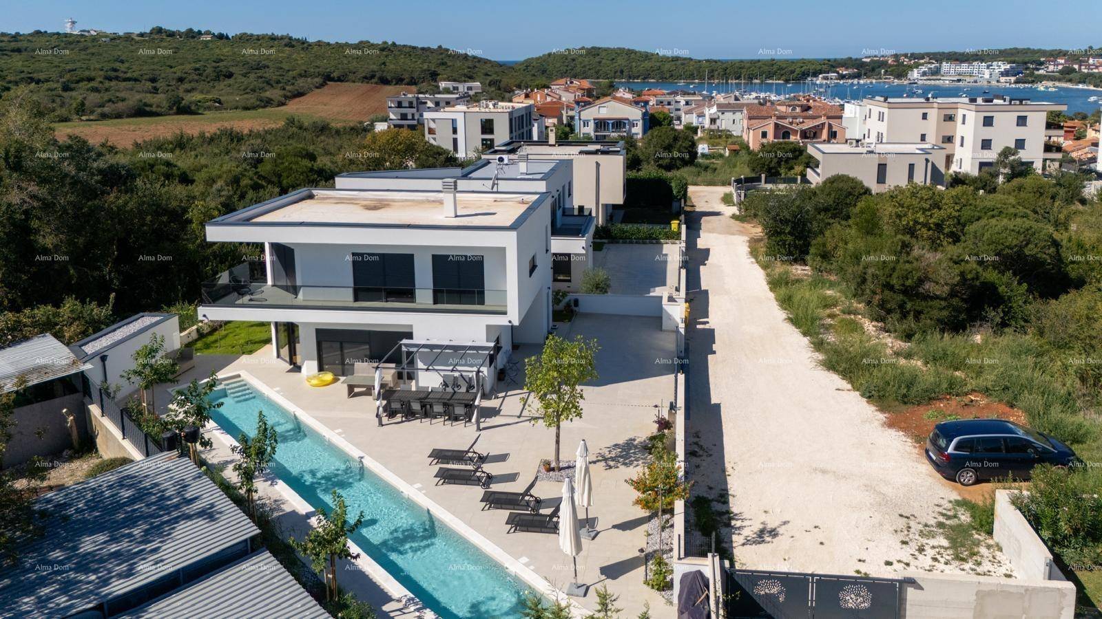 Moderne Villa mit langem Pool, großzügiger Terrasse und angrenzendem Parkplatz.