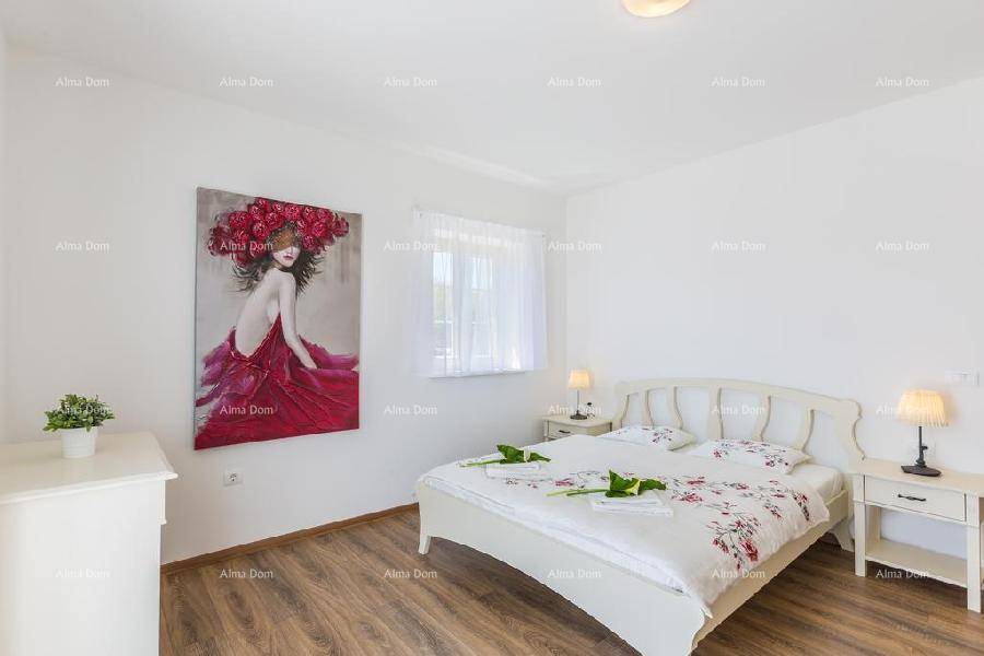 Helles Schlafzimmer mit Doppelbett, Holzboden und farbenfrohem Kunstwerk an der Wand.