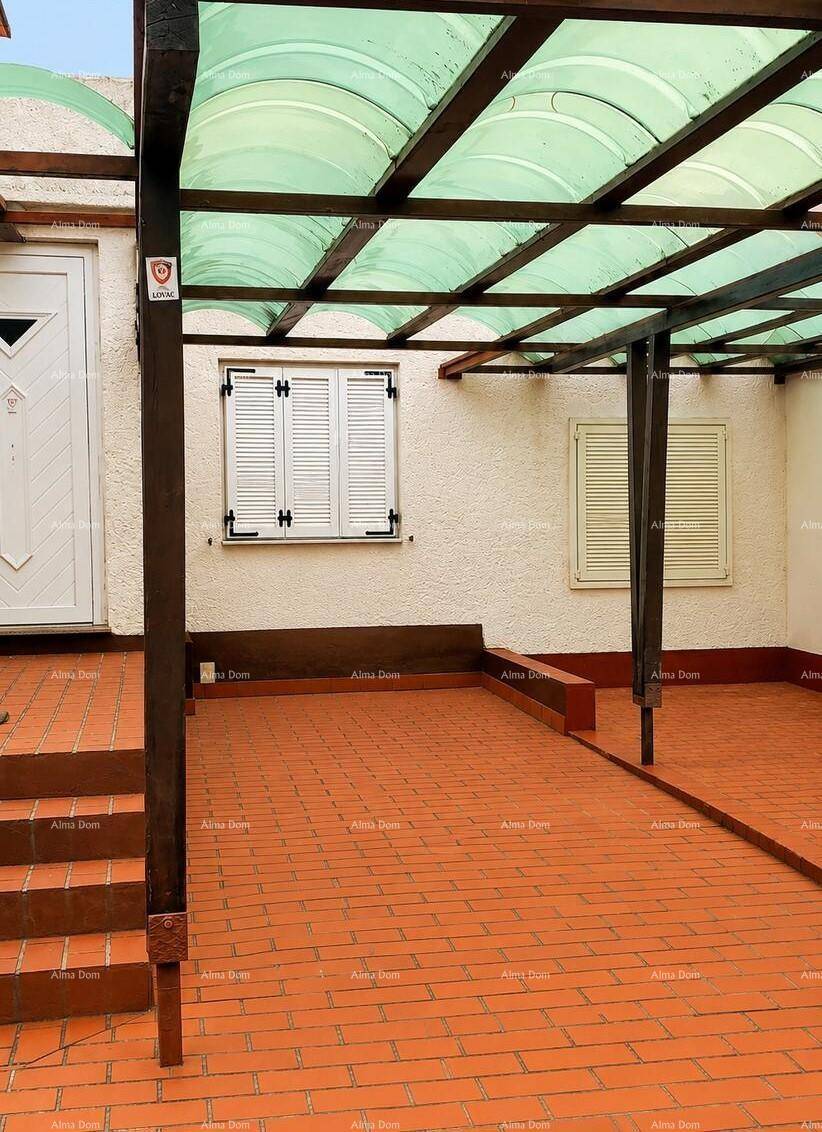 Überdachte Terrasse mit Rampe, Fliesenboden und Fensterläden, barrierefrei und funktional.