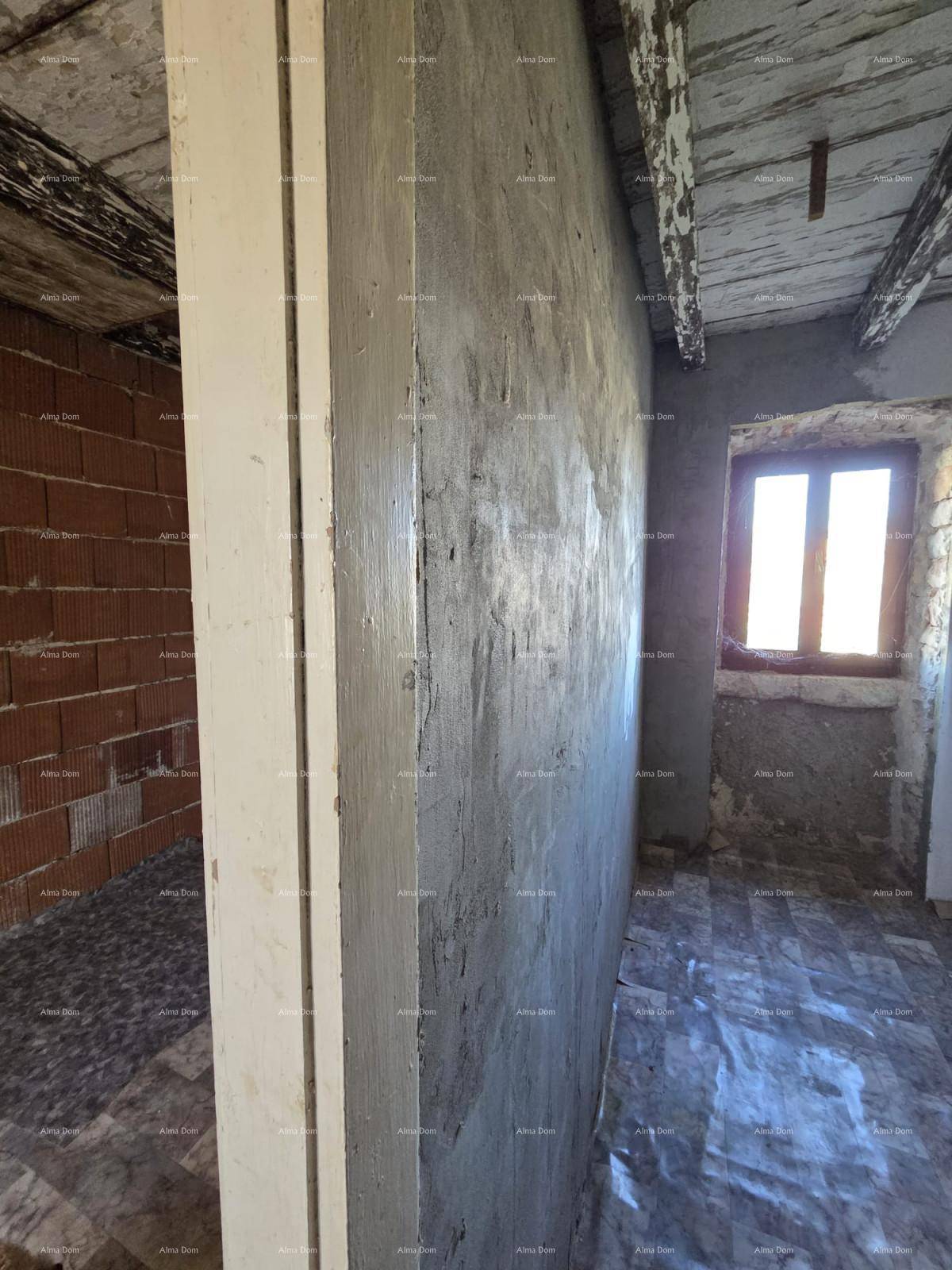 Innenraum im Rohbau mit unverputzten Wänden, sichtbaren Ziegeln und einem kleinen Fenster.