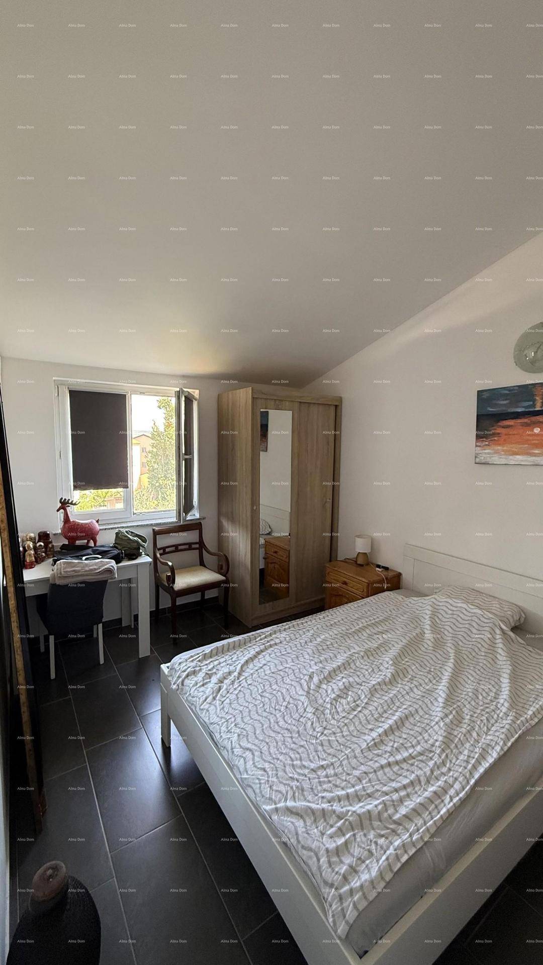 Schlafzimmer mit Doppelbett, Kleiderschrank, Schreibtisch und Fenster, auf dunklem Fliesenboden.