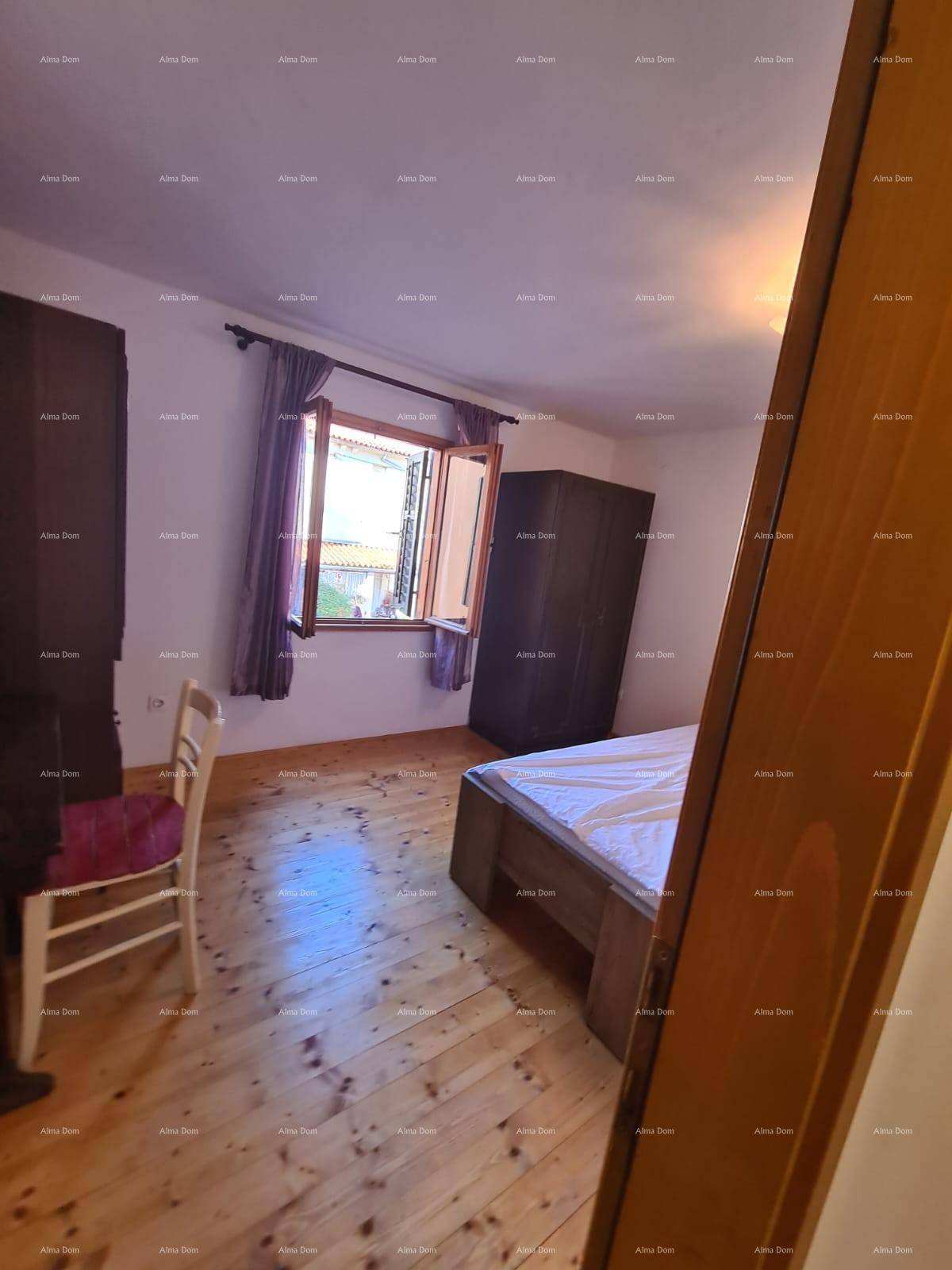 Schlafzimmer mit Holzboden, Fenster mit Vorhängen und einem Kleiderschrank, in traditionellem Stil eingerichtet.