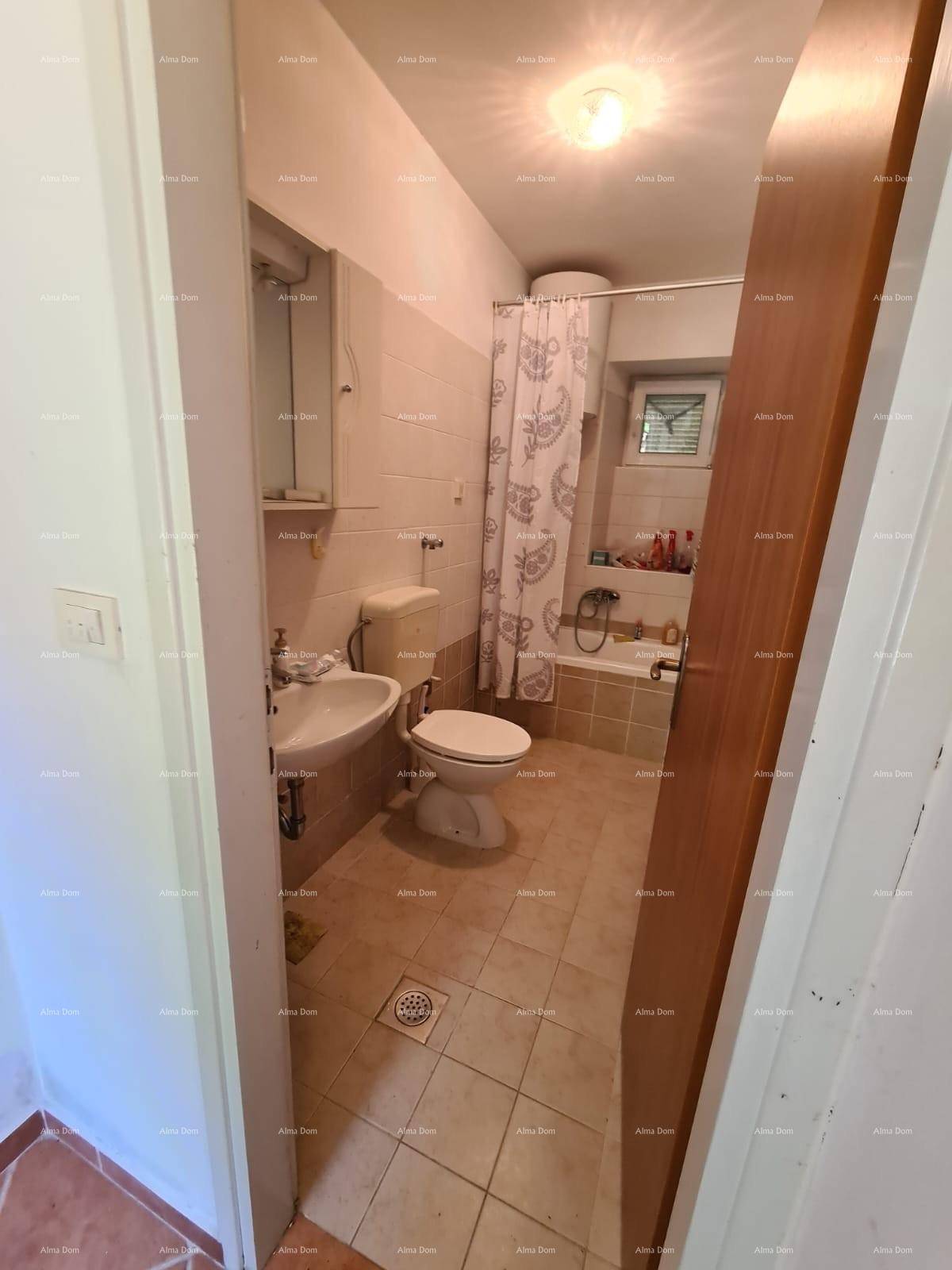 Badezimmer mit Toilette, Waschbecken und Badewanne mit Duschvorhang, hell gefliest.