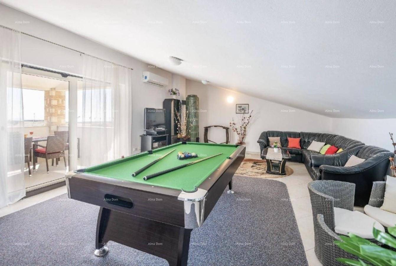 Geräumiges Wohnzimmer mit Billardtisch, Ledersofa und Zugang zu einem Balkon.