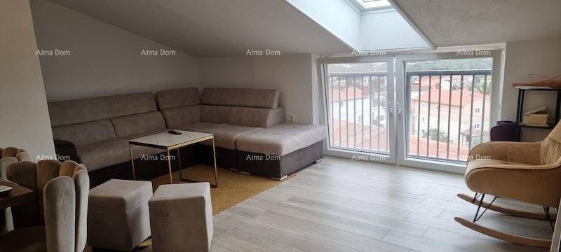 Gemütliches Wohnzimmer im Dachgeschoss mit Sofa, Schaukelstuhl und Dachfenster.