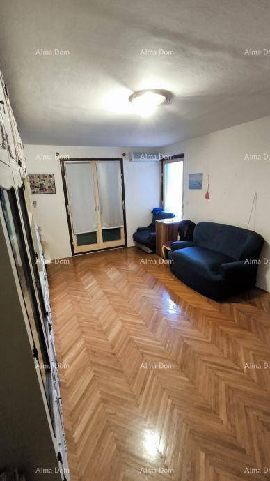Wohnzimmer mit elegantem Fischgrätparkett, dunklem Sofa und Zugang zum Balkon.